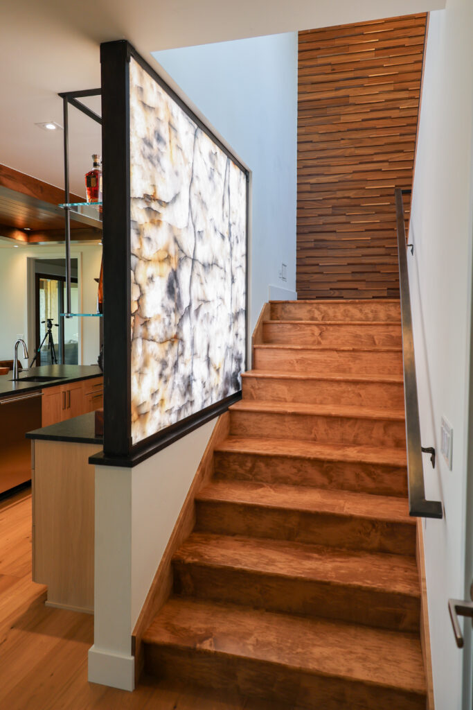 A wood paneled stair case with a light feature wall.