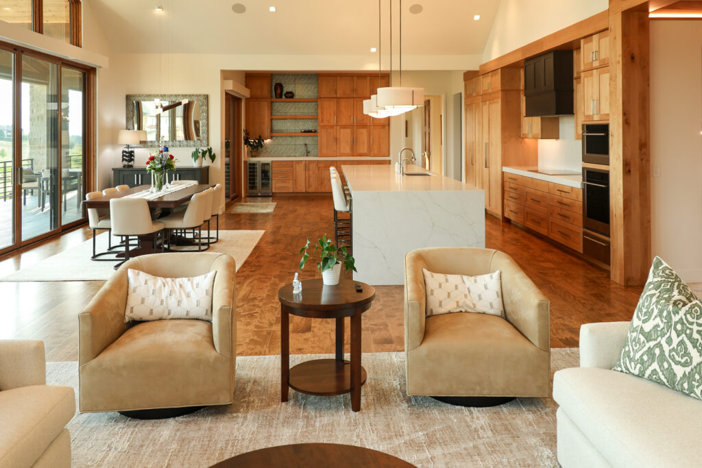 Large kitchen, living, and dining room space with a marble counter and light wood colored cabinets.