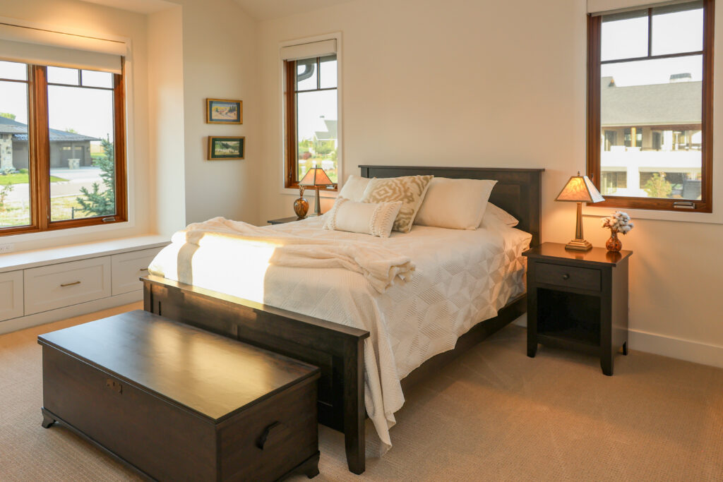 A primary bedroom suite with large windows and a bed with white decorative pillows and nightstands.