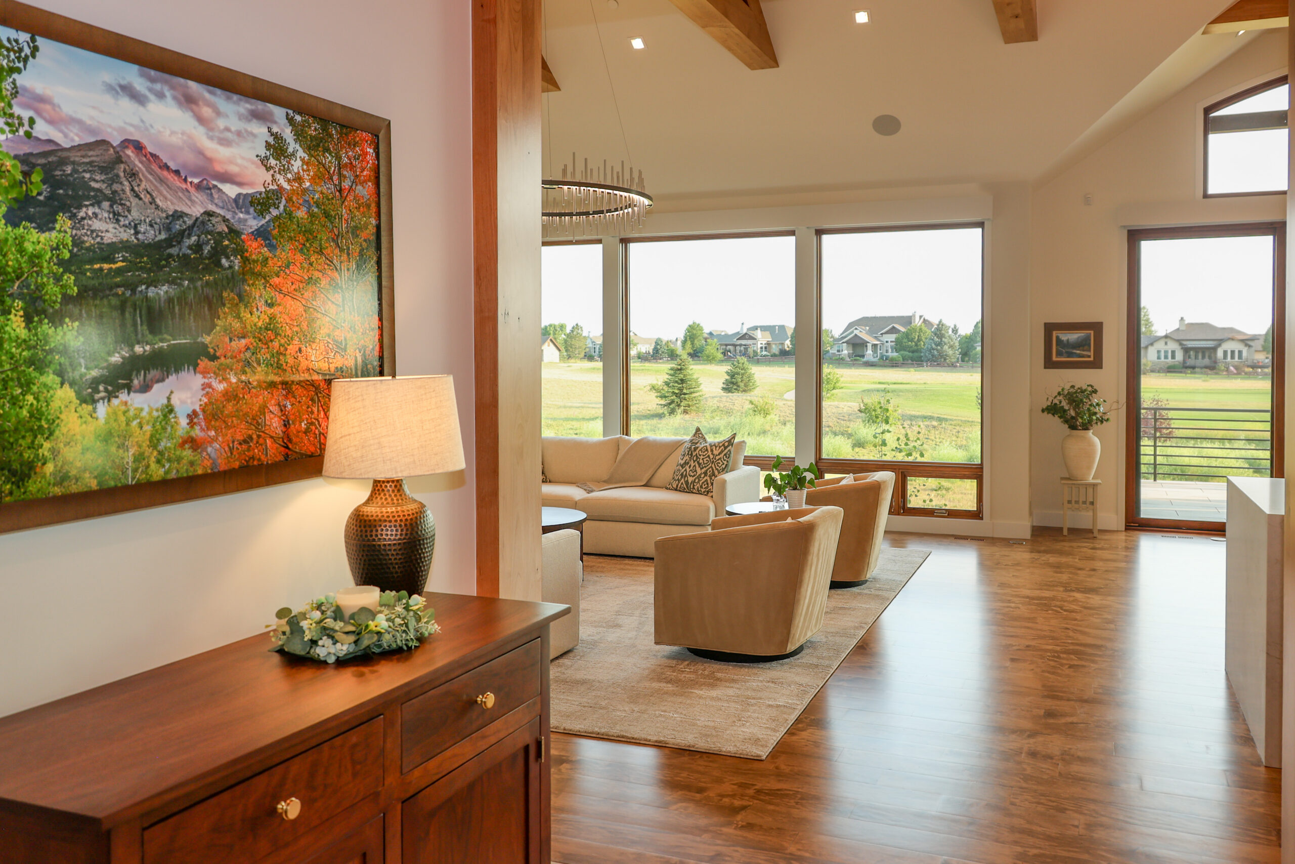 Bright living room space with floor to ceiling windows looking over a golf course.