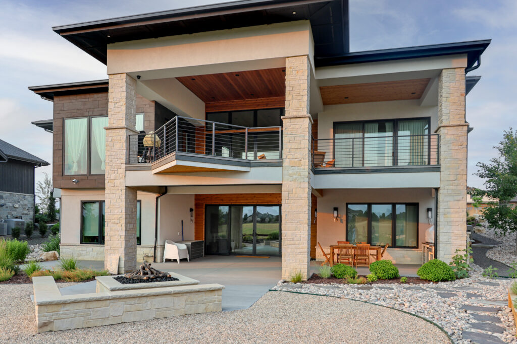 The outside of a large house with a two story patio and built in fireplace.