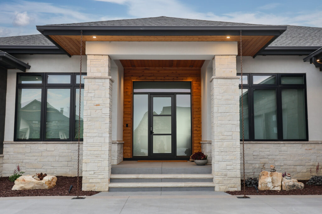 The outside of a house with a large glass door and stone pillars.