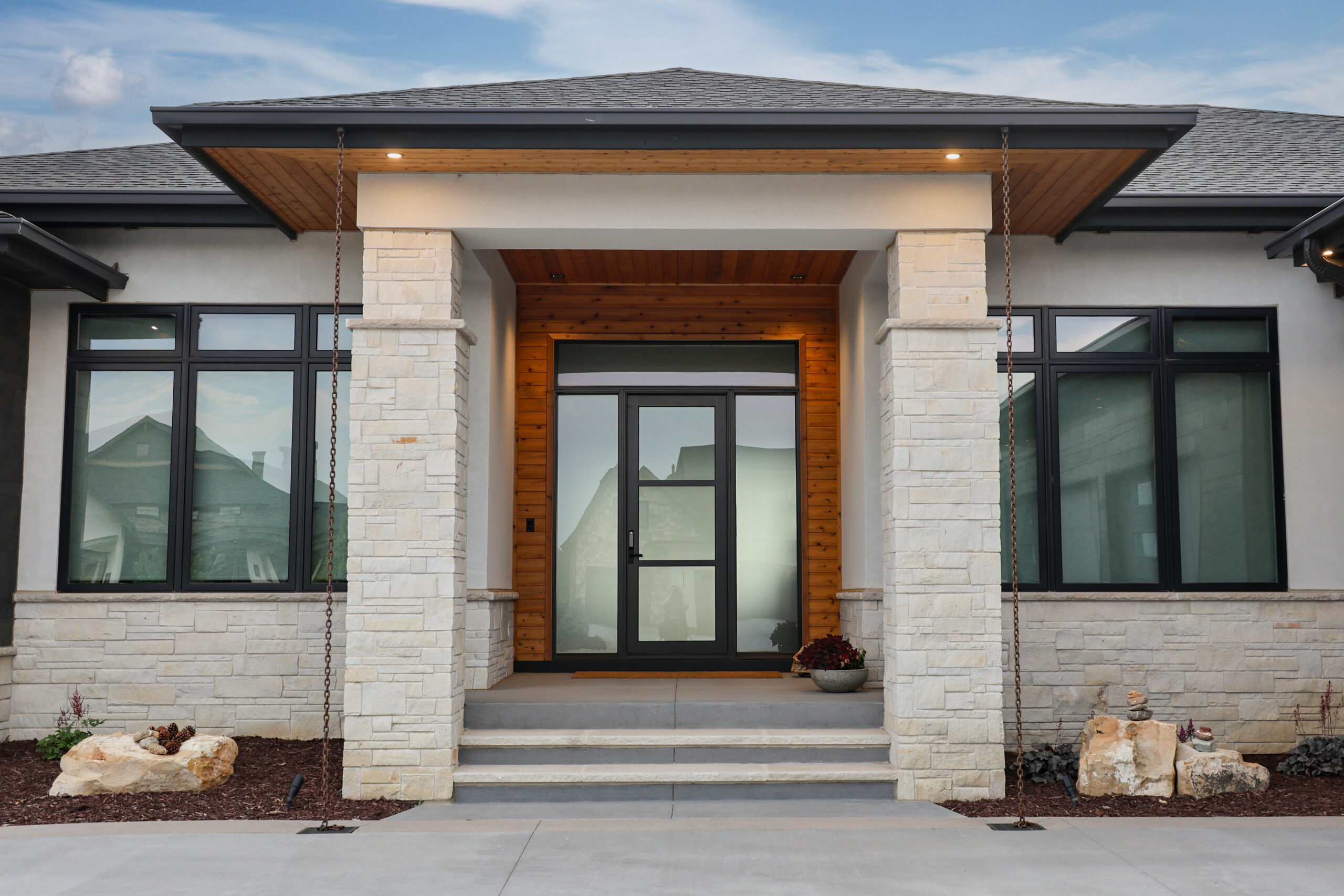 The outside of a house with a large glass door and stone pillars.