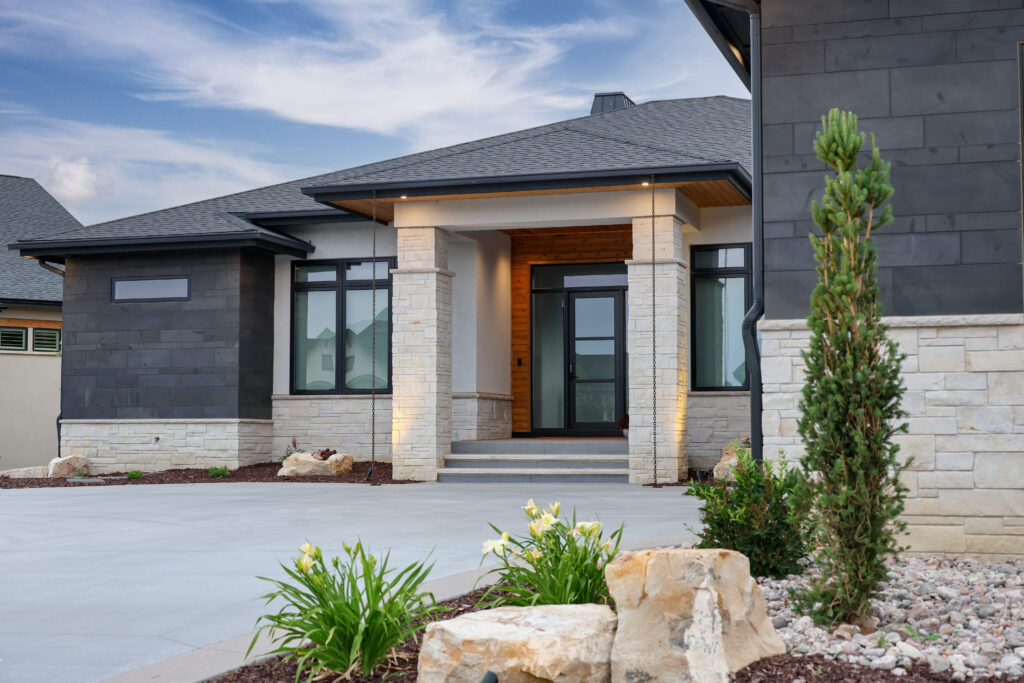The outside of a house with glass front doors and green plants.