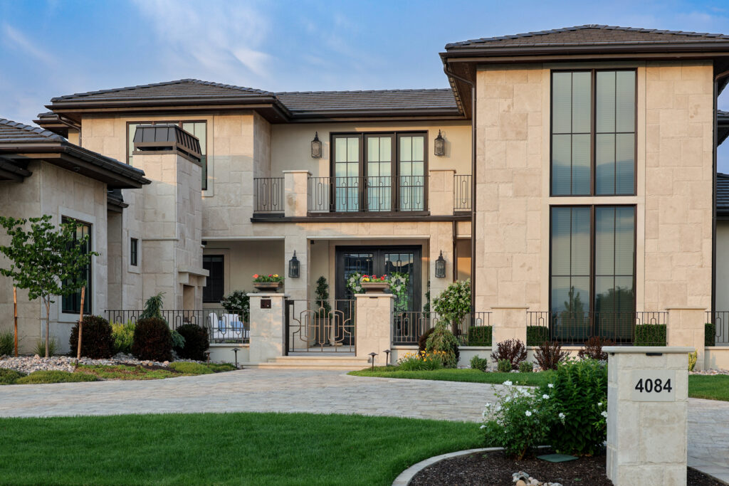 The outside of a house with green space in front and iron fencing.