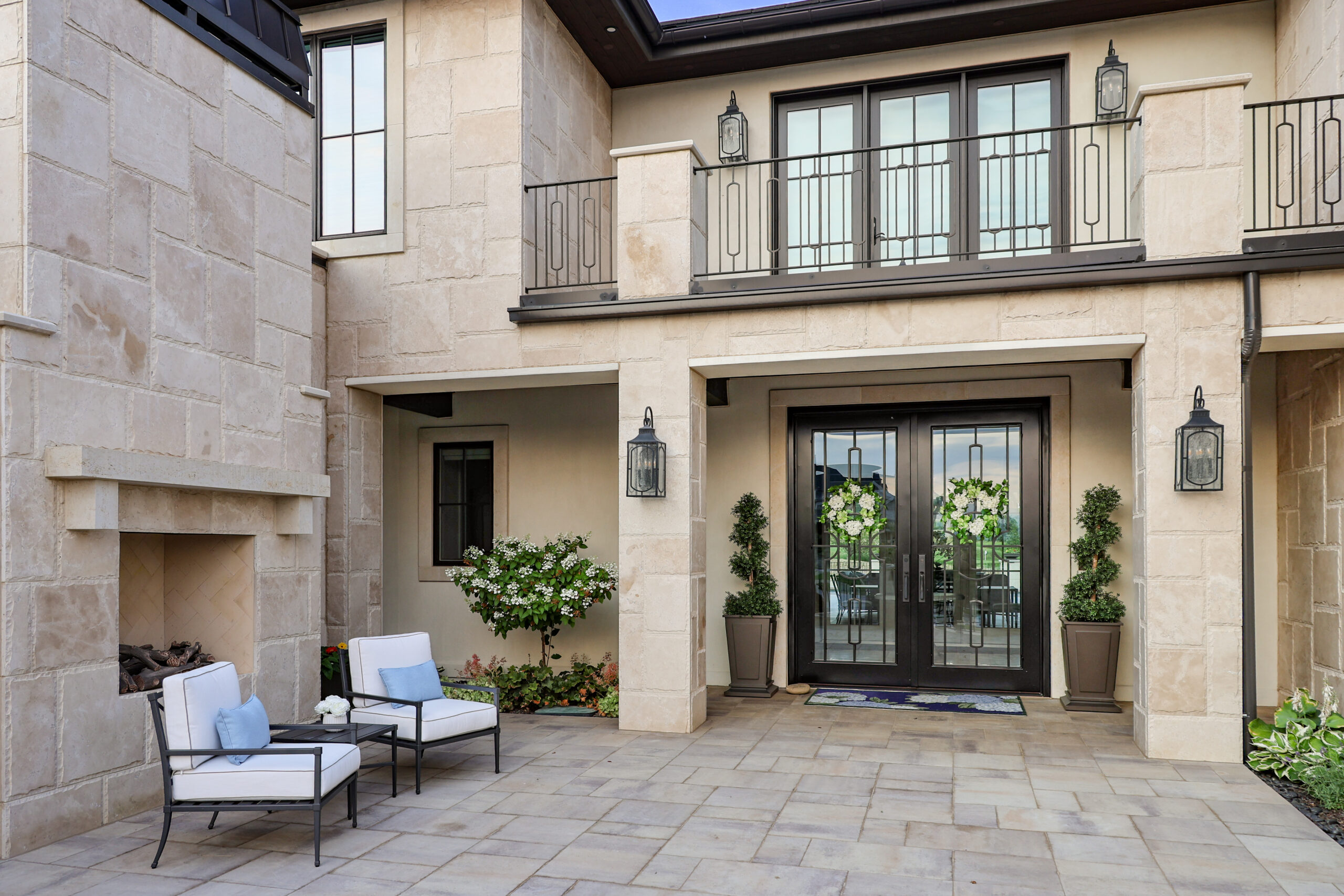 The outside of a house with glass double doors and patio chairs.
