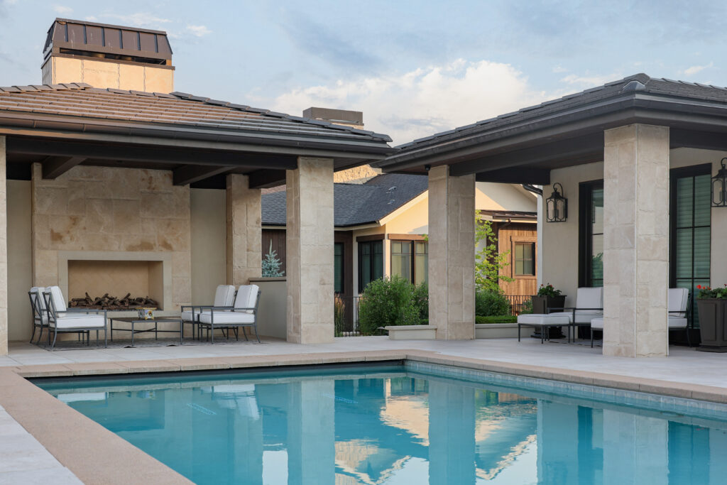 The outside of a house at sunset with a pool and patio furniture.