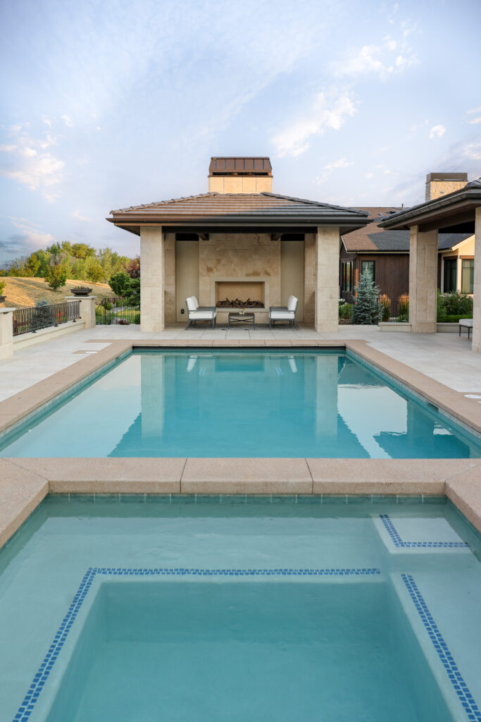 The backyard of a fireplace with a built in hot tub and pool.