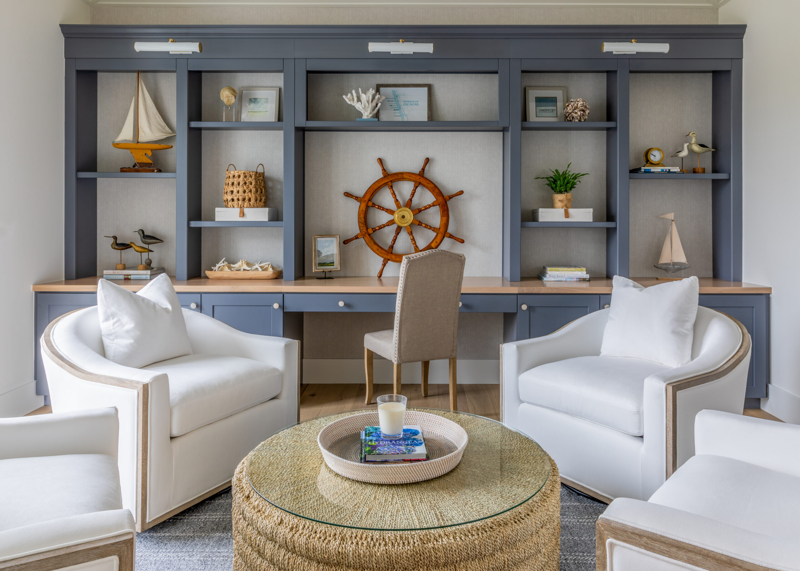 Beach themed built in shelves with decorations and puffy white chairs in front of the shelves.