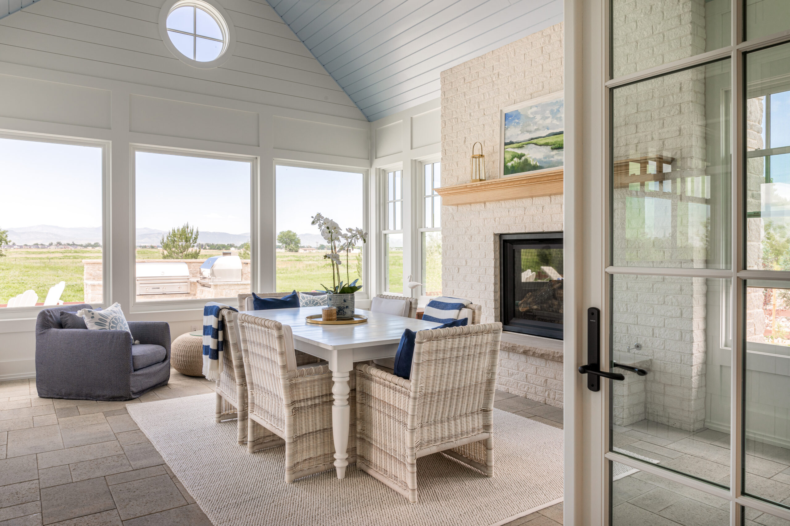 A light and spacious living room with wide windows and a white plank board ceiling with a dining room table in the middle.