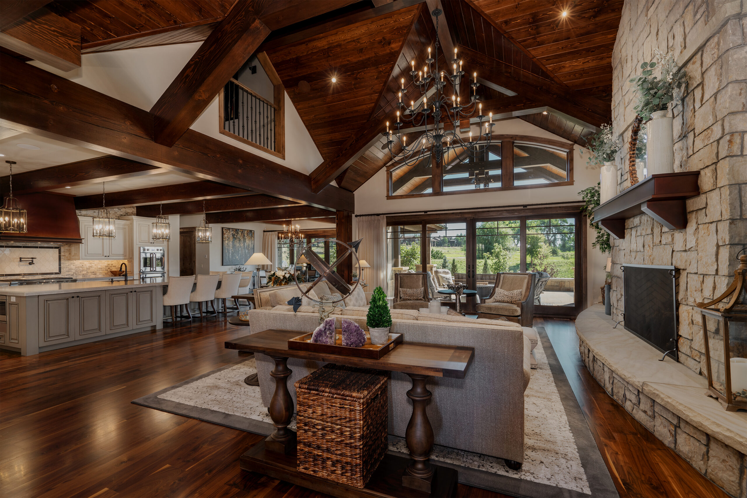 A living room and kitchen space with wood paneled ceiling and large windows.