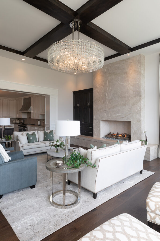 A white living room with a marble, floor to ceiling fireplace, white rug, and blue and white furniture.